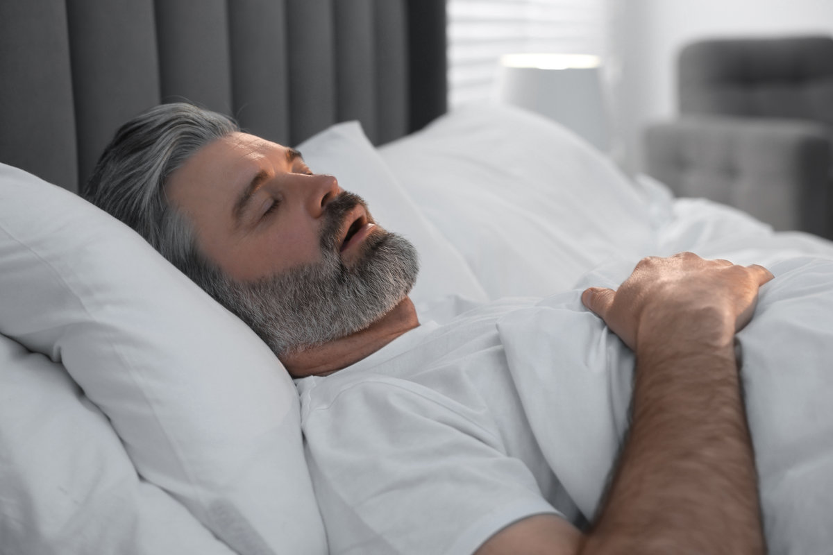 Man snoring while sleeping in bed at home